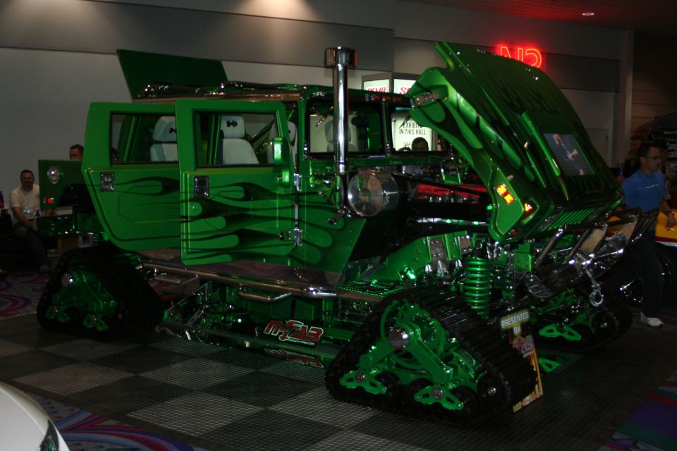 Custom green vehicle with flame graphics and tracks instead of wheels. Hood is open, showing engine components
