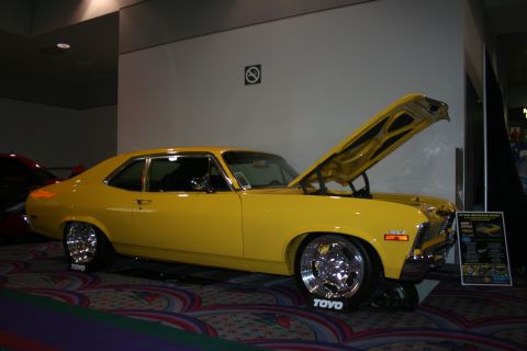 1998 Ford Crown Victoria - A yellow coupe with its hood open, displaying custom chrome wheels and a lowered stance.