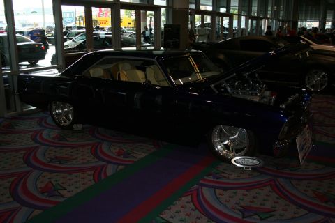 1998 Ford Crown Victoria - A customized coupe is displayed indoors with its hood open, revealing the engine bay.