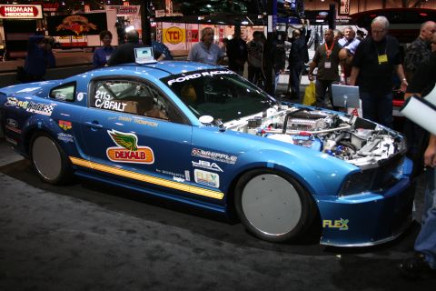 1998 Ford Crown Victoria - A blue Ford Mustang race car is displayed with its hood open, revealing the engine and numerous sponsor decals.