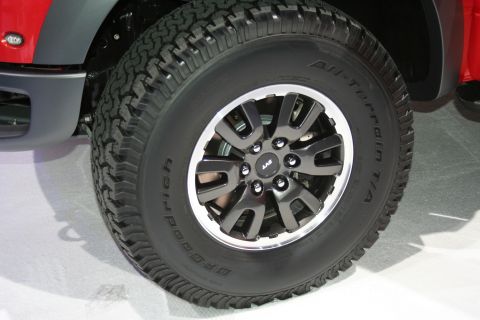 1998 Ford Crown Victoria - Close-up of a red vehicle's wheel and tire assembly, BFGoodrich All-Terrain T/A tires and an SVT-branded rim.