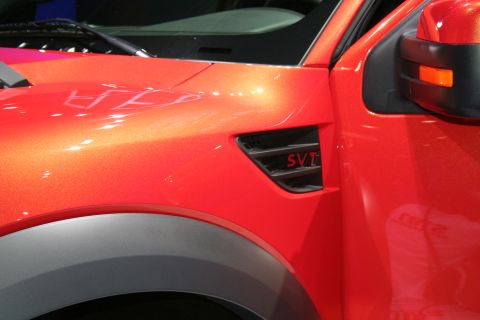 1998 Ford Crown Victoria - Close-up of an orange truck's fender, highlighting the SVT badge and vent detail.