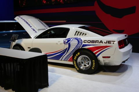 1998 Ford Crown Victoria - A white Ford Mustang Cobra Jet is displayed with its hood open, custom graphics and racing tires.