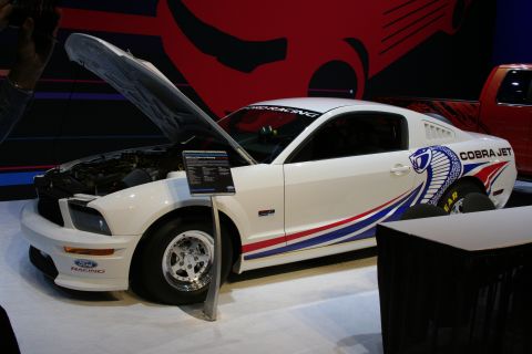 1998 Ford Crown Victoria - A white Ford Mustang Cobra Jet is displayed with its hood open, racing stripes and the 'Cobra Jet' decal.