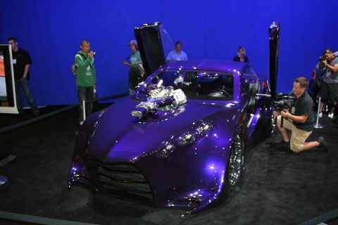 1998 Ford Crown Victoria - A custom purple car with an exposed engine and unique doors is on display, attracting photographers.