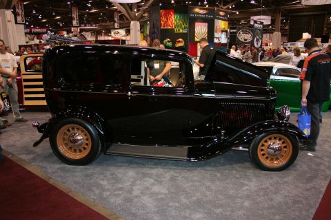 1998 Ford Crown Victoria - A vintage black sedan with distinctive tan wheels is displayed indoors.