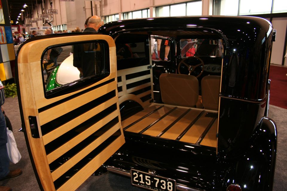 Black sedan delivery with wood-paneled rear door and bed, rear view