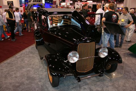 1998 Ford Crown Victoria - A black vintage sedan is displayed indoors with its hood open, showing the engine bay.