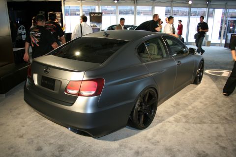 1998 Ford Crown Victoria - A matte gray sedan with custom black rims is displayed indoors, possibly at a car show.
