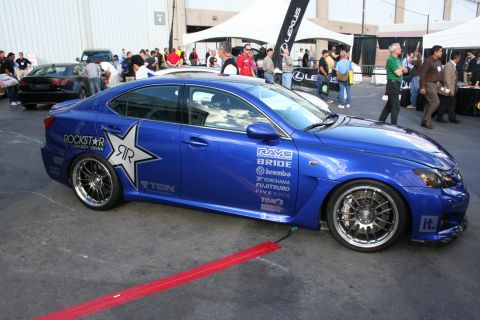 1998 Ford Crown Victoria - A blue sedan with racing decals is parked outdoors near a Lexus tent.
