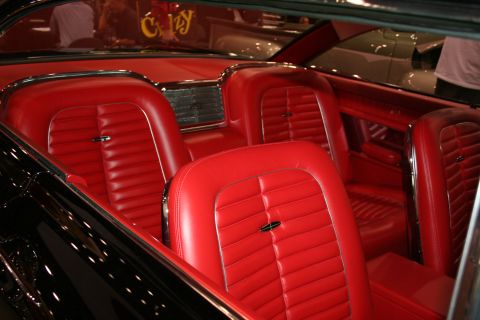 1998 Ford Crown Victoria - The interior of a classic car features bright red vinyl seats and chrome accents.