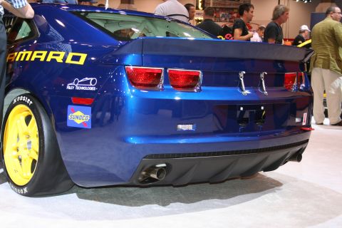 1998 Ford Crown Victoria - The rear of a blue race car is shown, racing decals and yellow-rimmed tires.