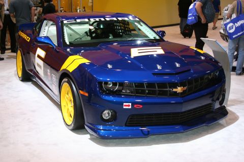 1998 Ford Crown Victoria - A blue Chevrolet Camaro race car with yellow accents is displayed indoors.