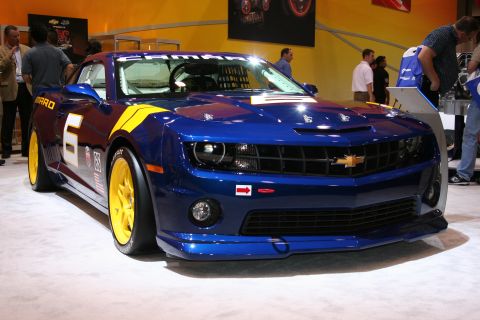 1998 Ford Crown Victoria - A blue and yellow race car with racing decals is displayed indoors.