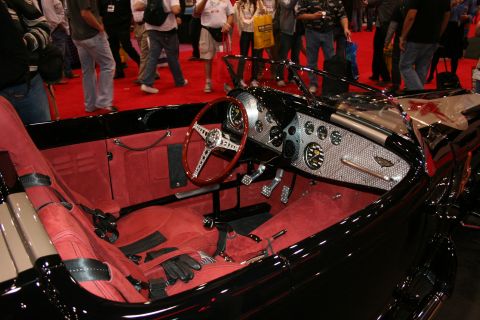1998 Ford Crown Victoria - The interior of a black convertible features red upholstery and a detailed chrome dashboard with multiple gauges.