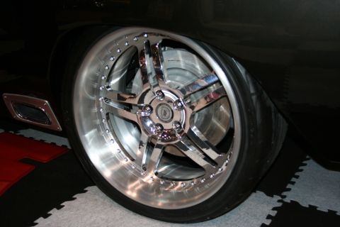 1998 Ford Crown Victoria - Close-up of a custom chrome wheel and tire on a black vehicle, showing aftermarket modifications.