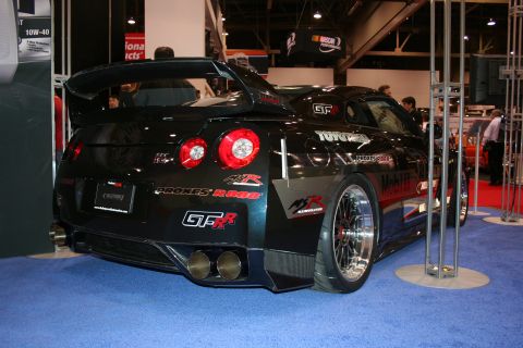 1998 Ford Crown Victoria - A black Nissan GT-R is displayed indoors with various sponsor decals on its body.
