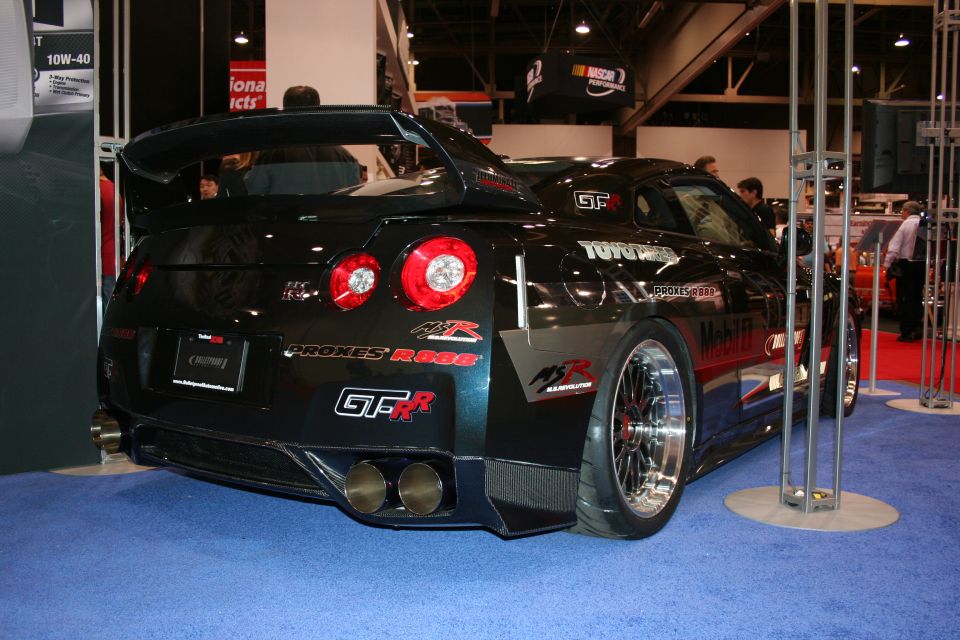 Black Nissan GT-R with large spoiler and custom wheels, rear view