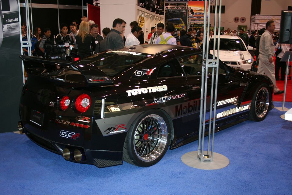 Black Nissan GT-R with racing decals and large spoiler, rear 3/4 view