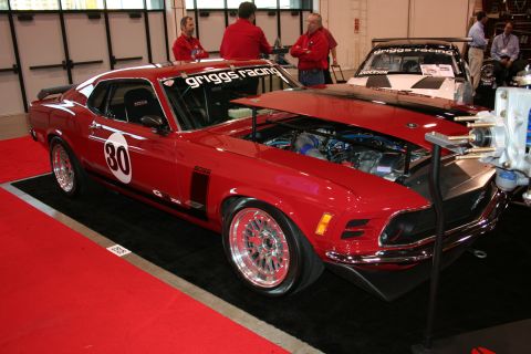 1998 Ford Crown Victoria - A red 1969 Ford Mustang Boss 302 race car is displayed with its hood open, revealing the engine. The car features racing decals and is park…