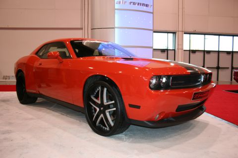 1998 Ford Crown Victoria - Orange Dodge Challenger with black racing stripes and custom wheels on display.