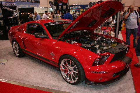 1998 Ford Crown Victoria - Red Ford Mustang Shelby GT500 on display at an auto show, hood open to reveal the engine.