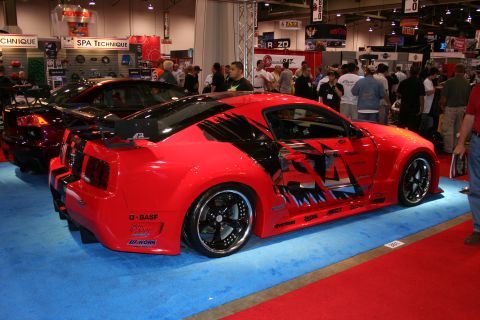 1998 Ford Crown Victoria - A heavily modified red sports car with custom graphics is displayed at an auto show.