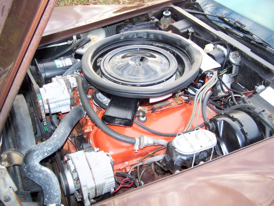 Engine bay with orange V8 engine, air cleaner, alternator, and brake master cylinder