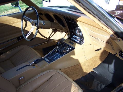 1991 Ford LTD Crown Victoria - The interior of a 1970s Corvette features tan leather seats, a wood-grain accented dashboard, and a prominent center console with a shifter.