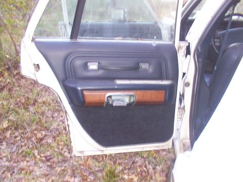 1991 Ford LTD Crown Victoria - Interior door panel of a 1991 Ford Crown Victoria LTD shows wood trim and black carpet.