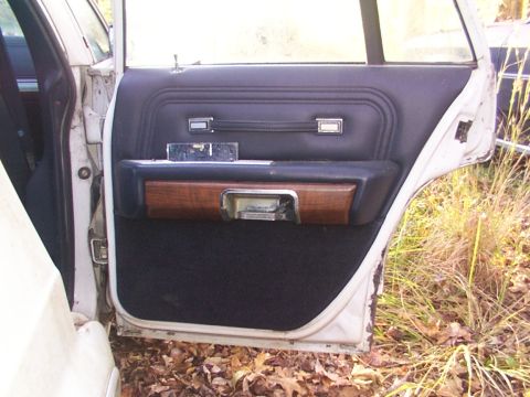 1991 Ford LTD Crown Victoria - Interior of a car door shows wear and tear on the wood trim and upholstery.