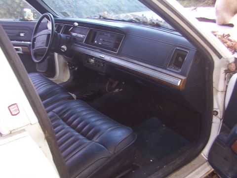 1991 Ford LTD Crown Victoria - Close-up of the interior door panel of a white vehicle, showing the armrest and door handle.