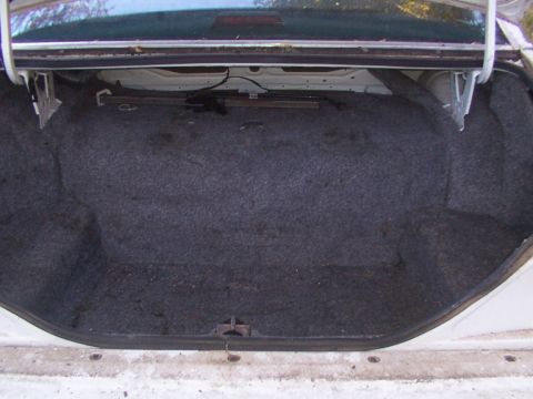 1991 Ford LTD Crown Victoria - The trunk of a 1991 Ford Crown Victoria LTD shows its grey carpet lining and the open lid mechanism.