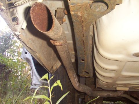 1991 Ford LTD Crown Victoria - The rusty exhaust system and undercarriage of a vehicle are shown in this close-up view.