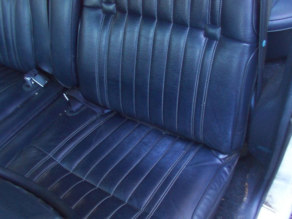 Dark blue vinyl car seats with white stitching, showing the rear bench seat and part of the front seat