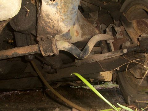1991 Ford LTD Crown Victoria - A close-up view of the rusty undercarriage and suspension of a vehicle, showing various mechanical parts.