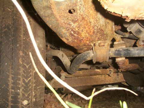 1991 Ford LTD Crown Victoria - The heavily rusted undercarriage of a vehicle shows significant wear and tear on its suspension components.