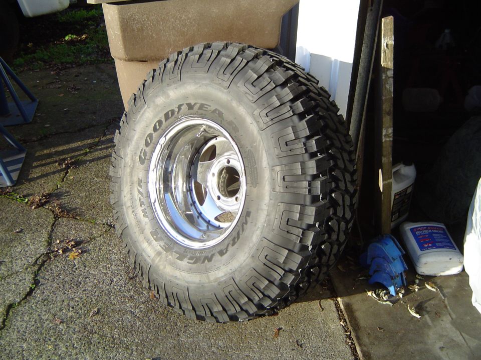 Goodyear mud tire on a chrome wheel leaning against a wall