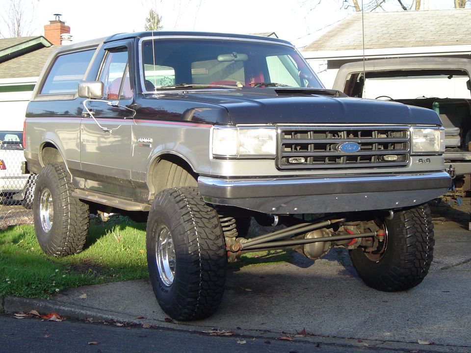 Lifted two-tone gray Ford Bronco SUV on large off-road tires, front 3/4 view in driveway