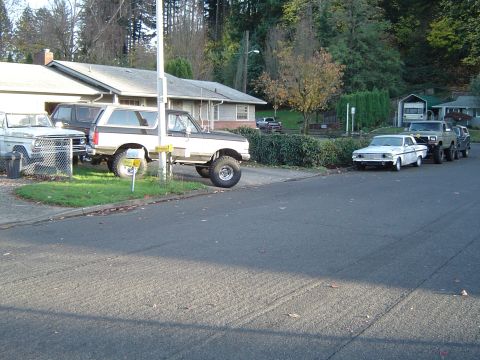 1989 Ford Bronco - A lifted 1989 Ford Bronco is parked in a driveway alongside other vehicles.