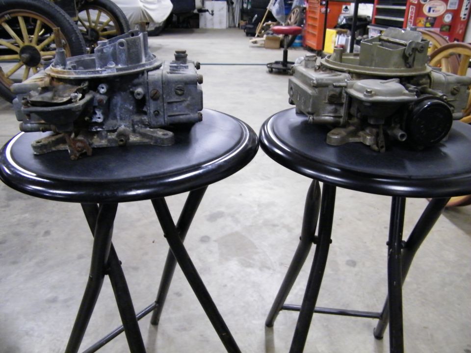 Two carburetors on black folding stools