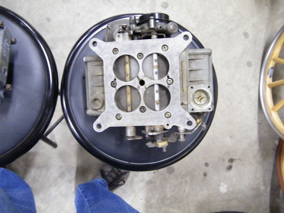 Close-up of a four-barrel carburetor mounted on a black air cleaner base