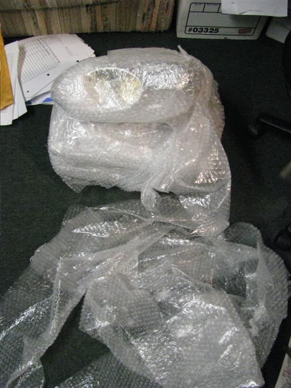 Car part in bubble wrap with "#03325" visible on a box