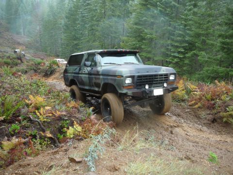 1991 Ford Bronco - Ford Bronco navigating a wet, wooded trail with other vehicles present.