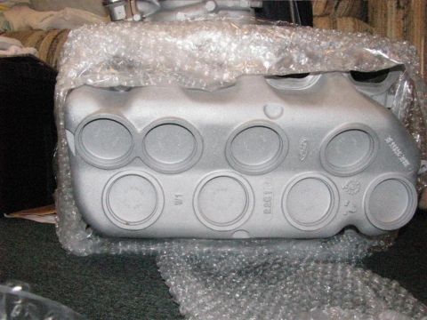 2003 Mercury Marauder - A silver engine intake manifold, wrapped in bubble wrap, is shown with visible casting marks and circular ports.
