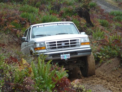 1991 Ford Bronco - White Ford Bronco with "2 BIG BRONCOS 4X4 CLUB" sticker on windshield, navigating a muddy trail.