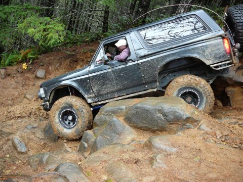 1991 Ford Bronco - This 1991 Ford Bronco is tackling a challenging off-road course with large rocks and mud.