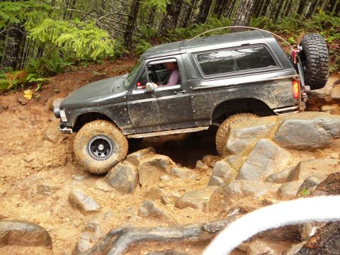 1991 Ford Bronco - This Ford Bronco is tackling a challenging off-road course with large rocks and mud.