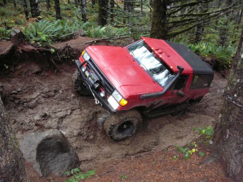 1991 Ford Bronco - Red 1991 Ford Bronco stuck in mud on a forest trail, equipped for off-roading.