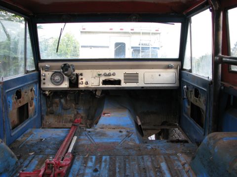 1967 Ford Bronco - The interior of a 1966 Ford Bronco reveals a bare cabin with a red jack on the floor.